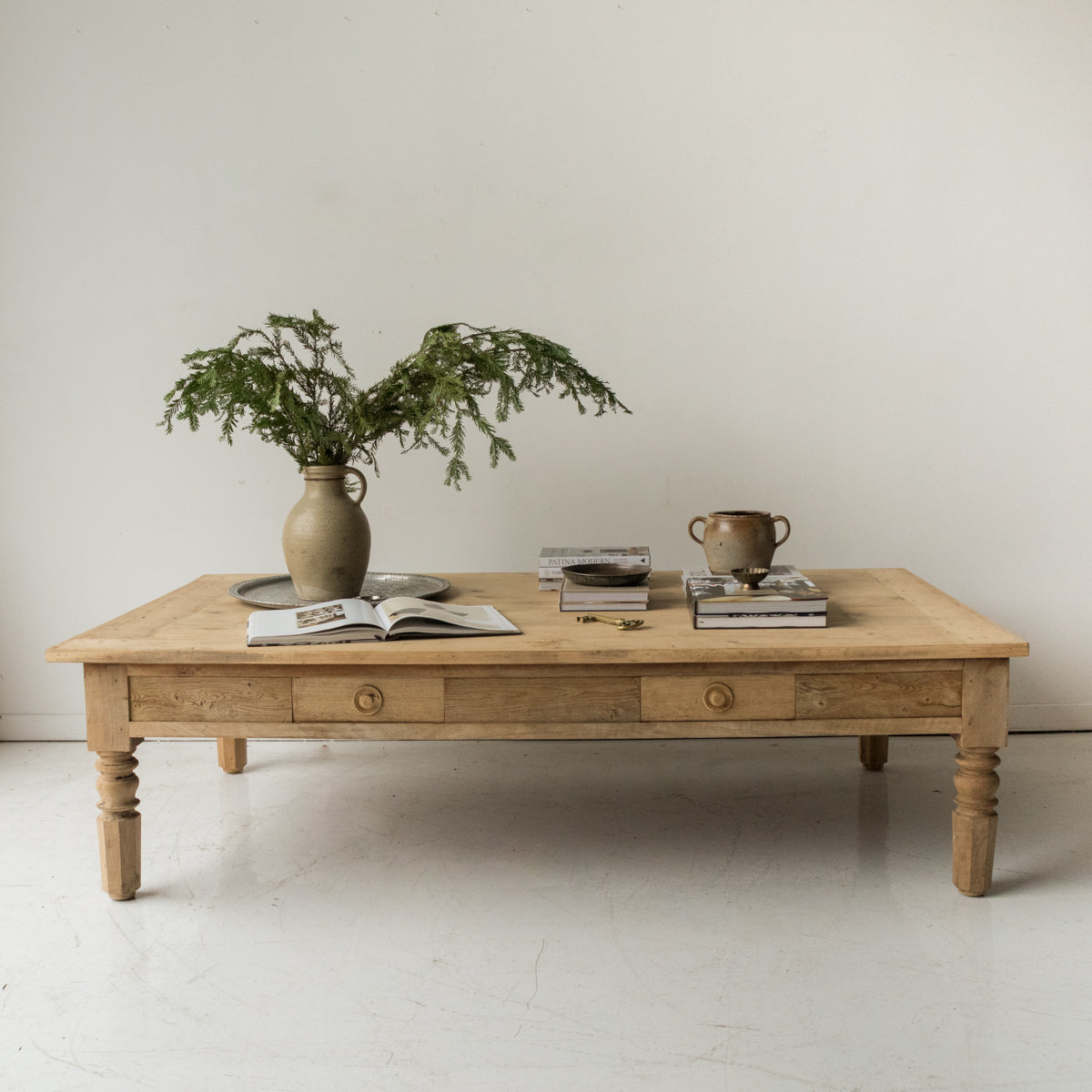 Wooden coffee table with decorative items including a vase, books, and a plant on a light background