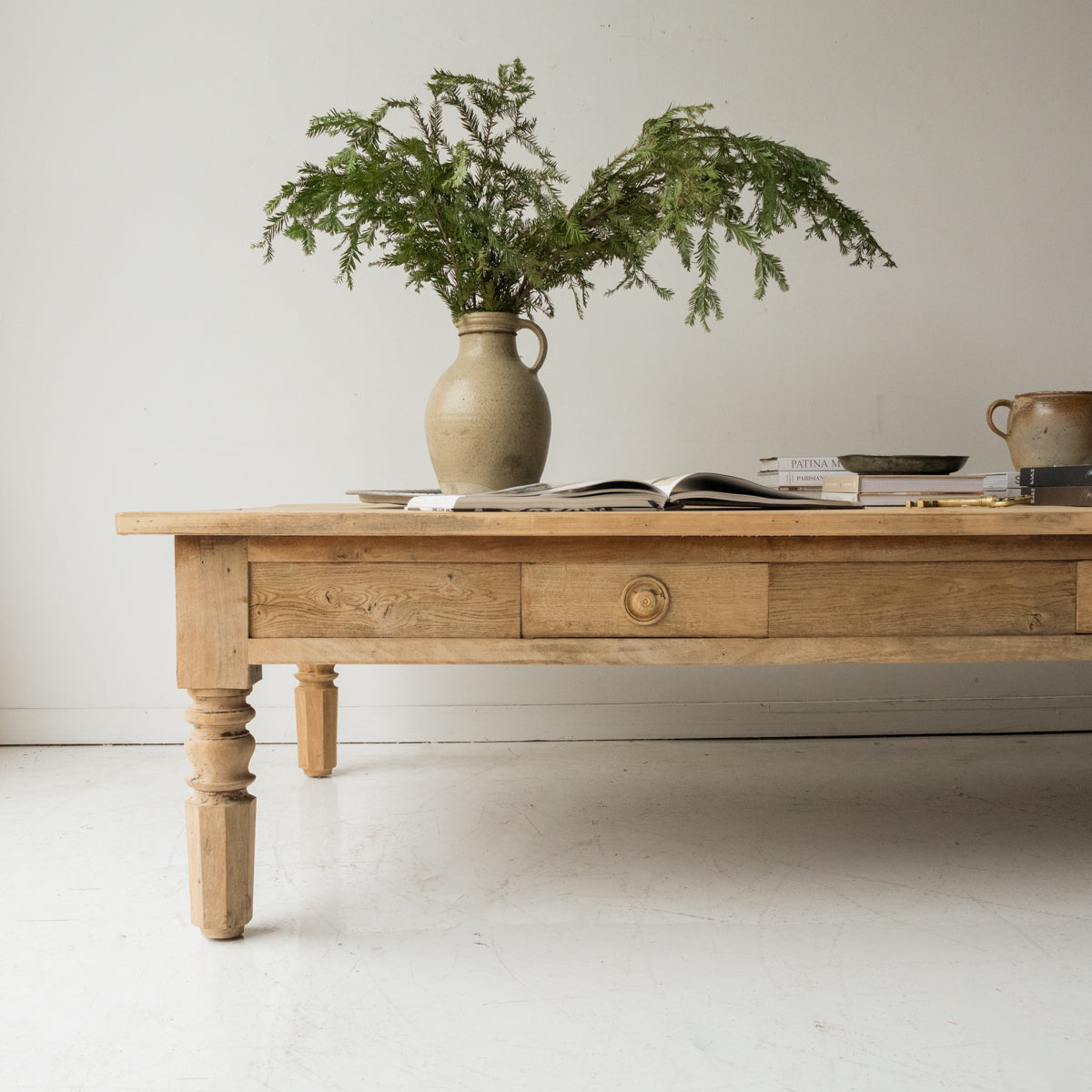 Wooden coffee table with a vase of greenery and books on a light background
