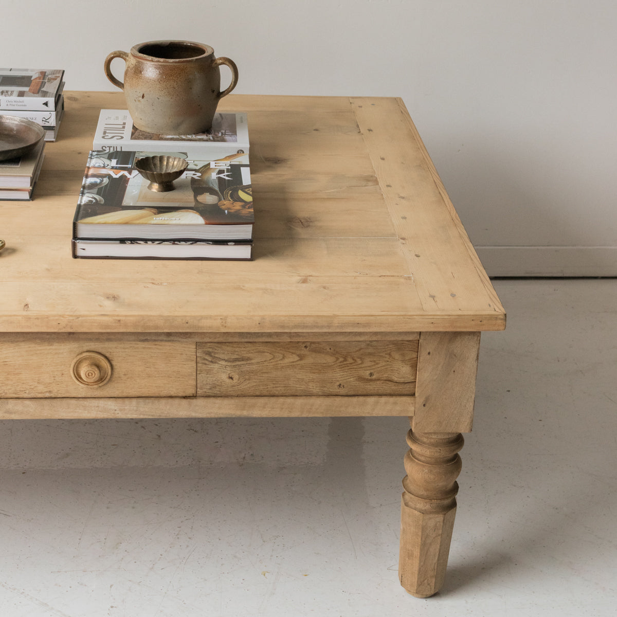 Wooden table with a ceramic mug and books on top against a plain background