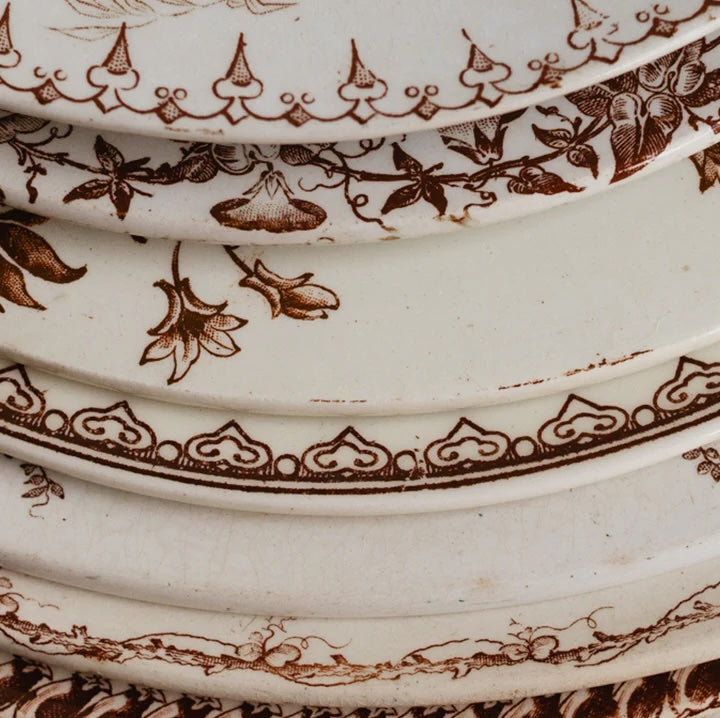 stack of brown transferware plates in different patterns
