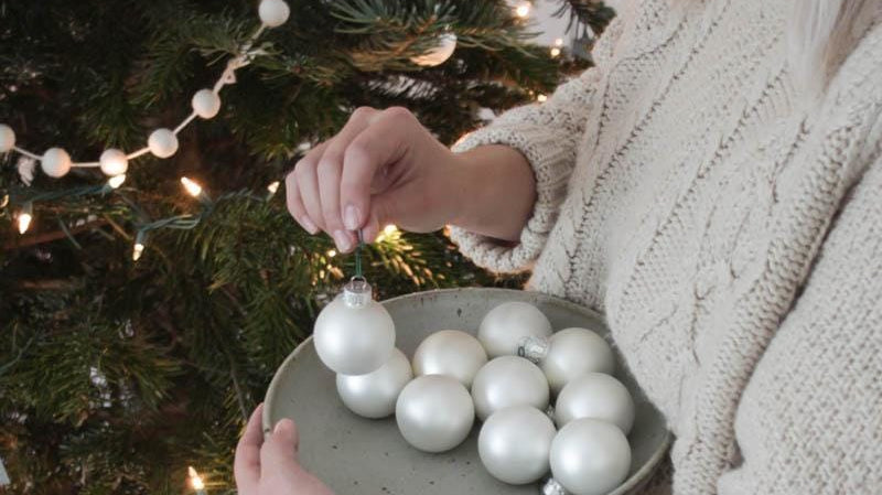 woman putting ornaments on a tree