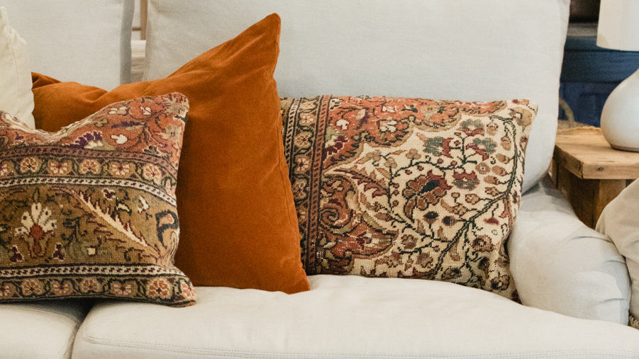Cozy living room with a white sofa, patterned cushions, and a wooden coffee table.