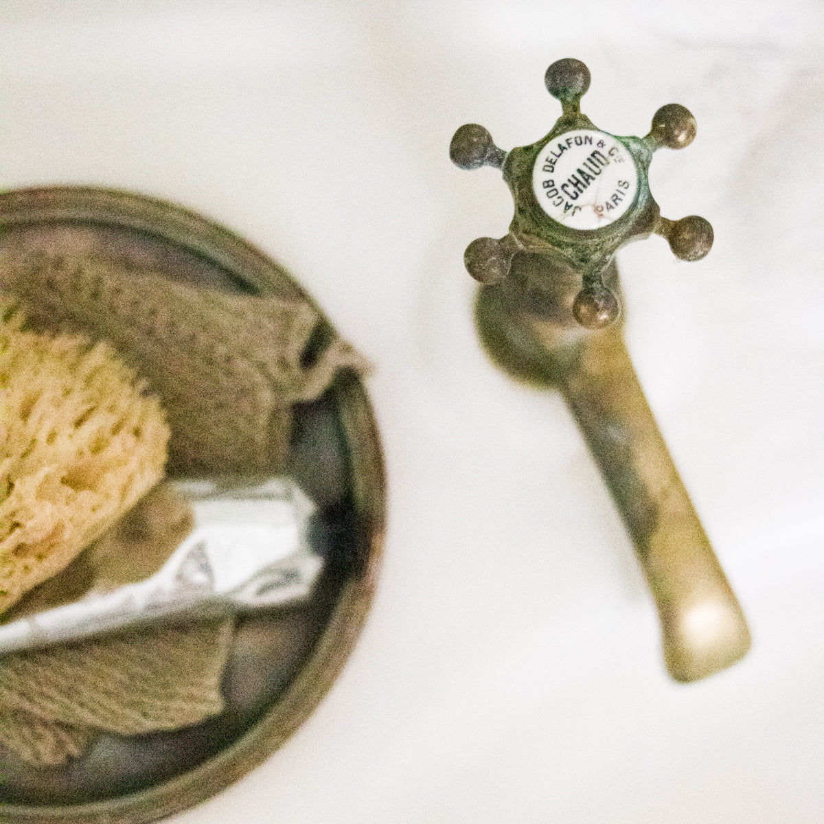 Vintage-style brass faucet with a green handle on a white background