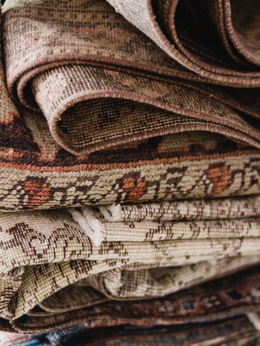 Stack of patterned rugs with various colors and designs.