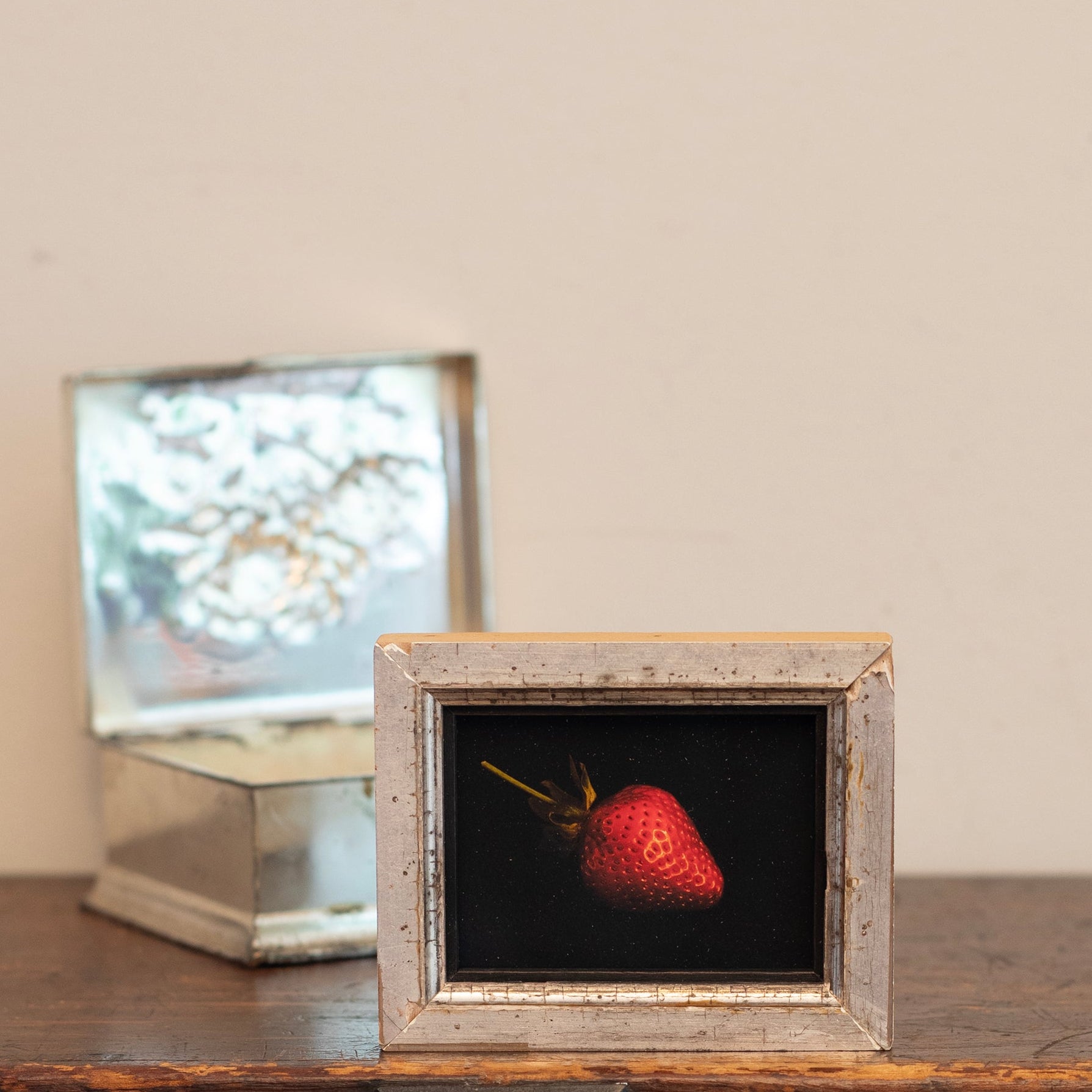 Framed picture of a strawberry on a wooden surface with a neutral background