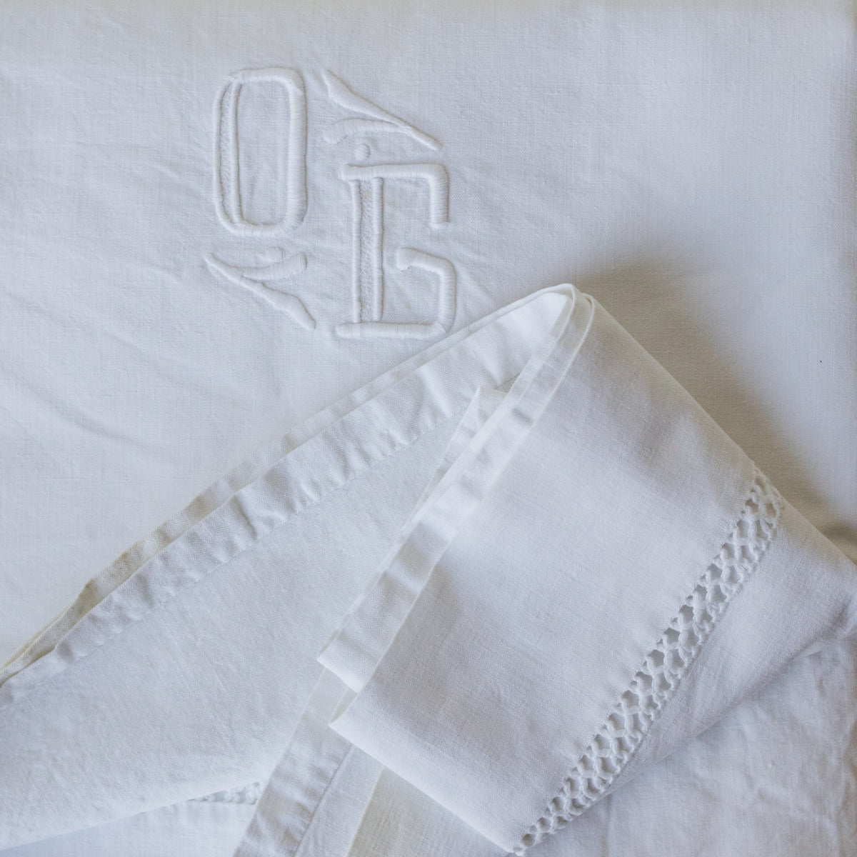 White linen napkin with lace trim and monogram on a white background
