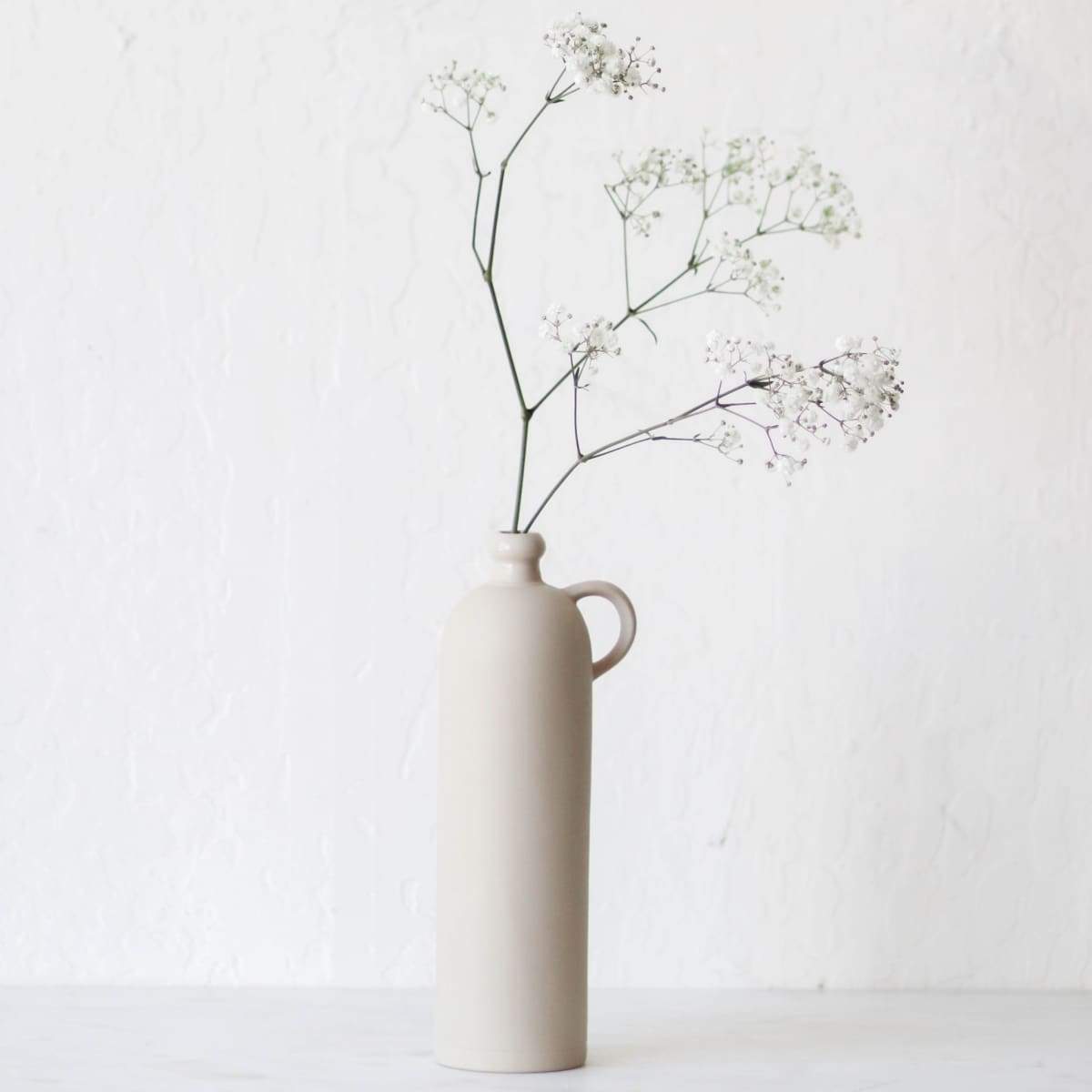 https://elsiegreen.com/cdn/shop/products/beer-bottle-with-handle-the-french-kitchen-ceramic-cider-core-white-vase-twig-383.jpg?v=1623432130